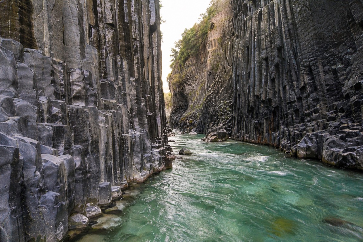 Dark basalt columns rising above the river in the Alcantara Gorges in Sicily
