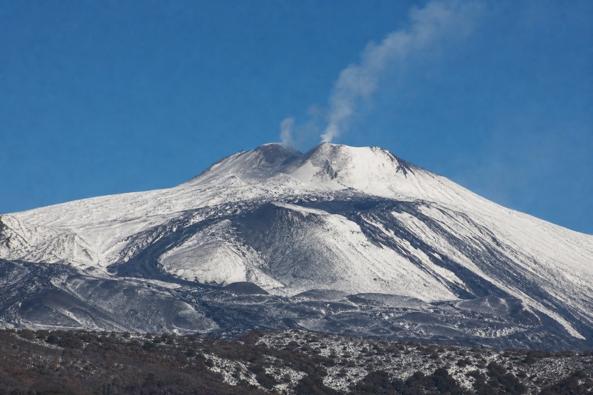 Snow-capped Mount Etna summit against a clear blue sky during the Mount Etna snow season