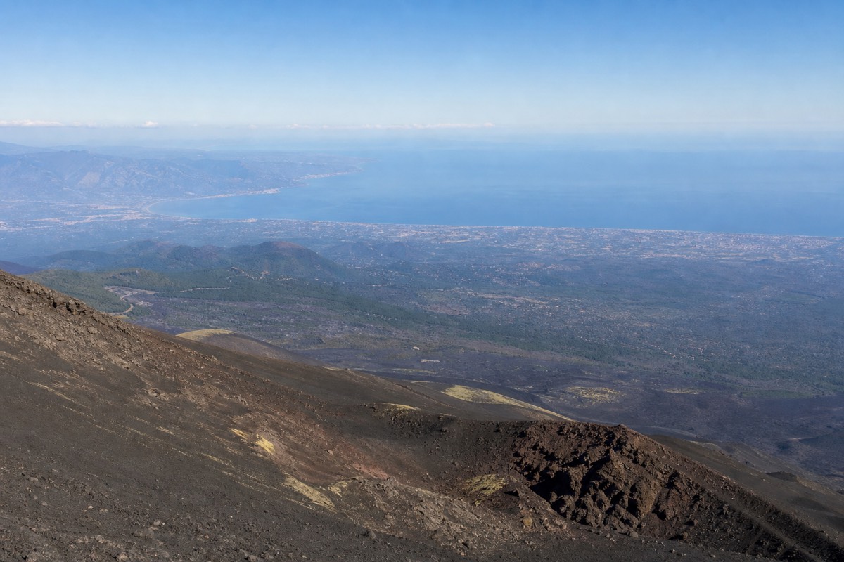 Volcanic slopes seen while hiking Mount Etna, with views toward the Ionian coast